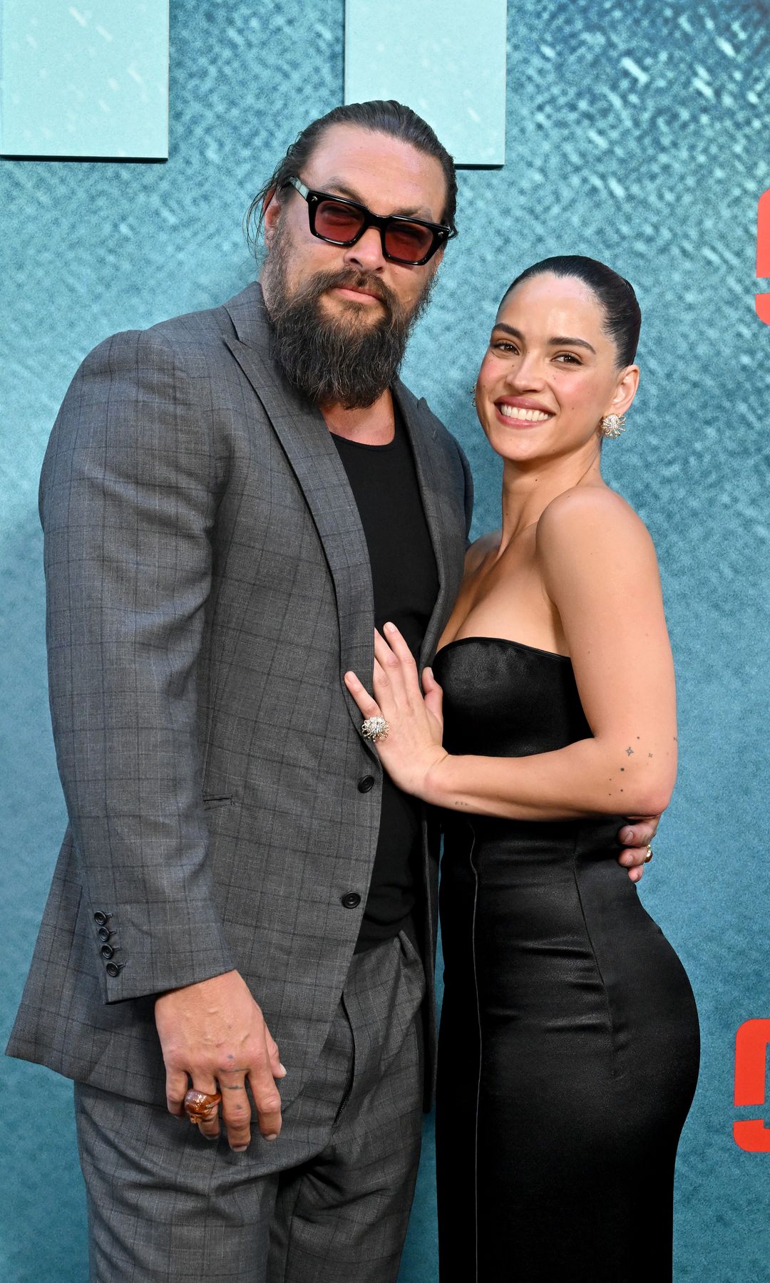Adria Arjona and Jason Momoa share a sweet kiss on the 'Onslaught' red carpet