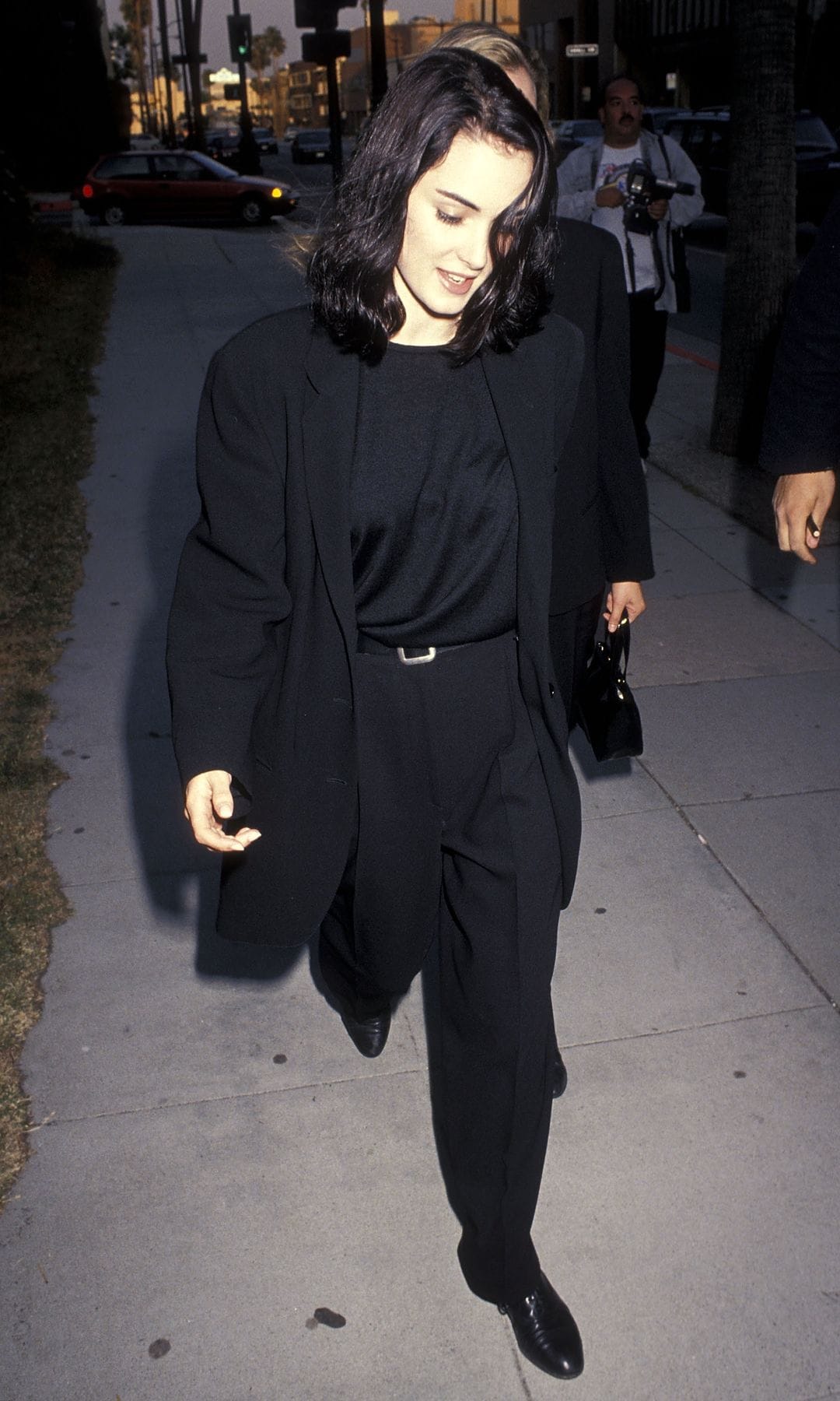  Winona Ryderin in1992 wearing a total black suit combined with a classic belt and loose natural hair.