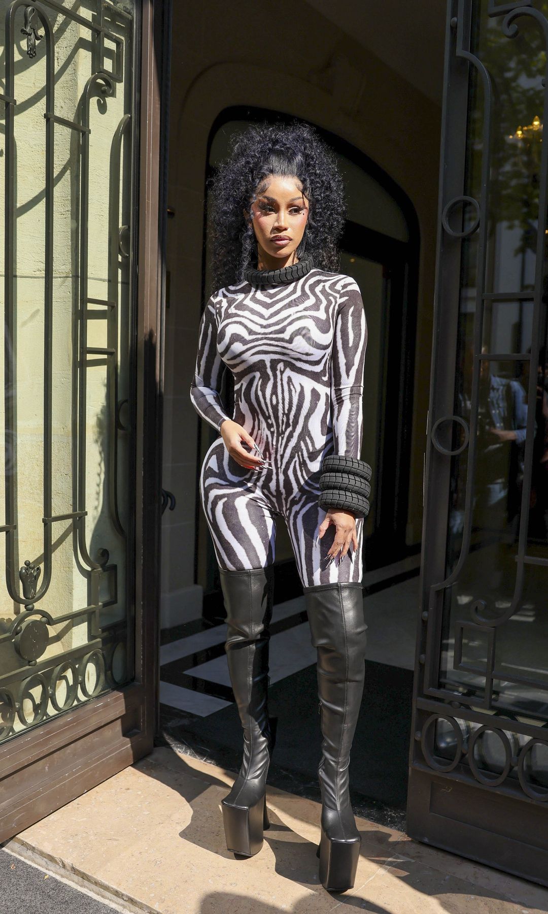Cardi B makes a striking appearance during Paris Fashion Week, wearing an eye-catching look featuring tire-inspired jewelry.
