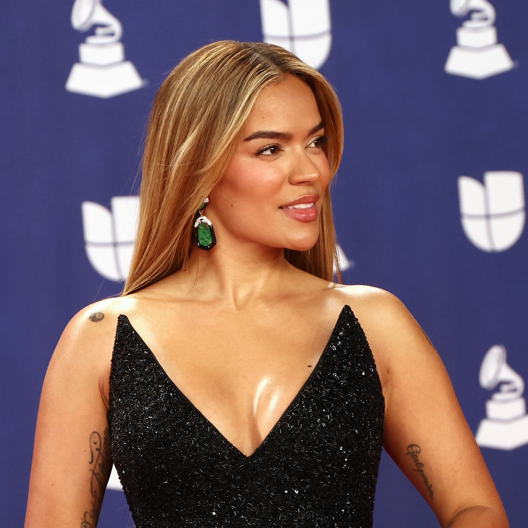 Karol G turns heads in dramatic black feathered gown with emerald accessories at the Latin Grammys
