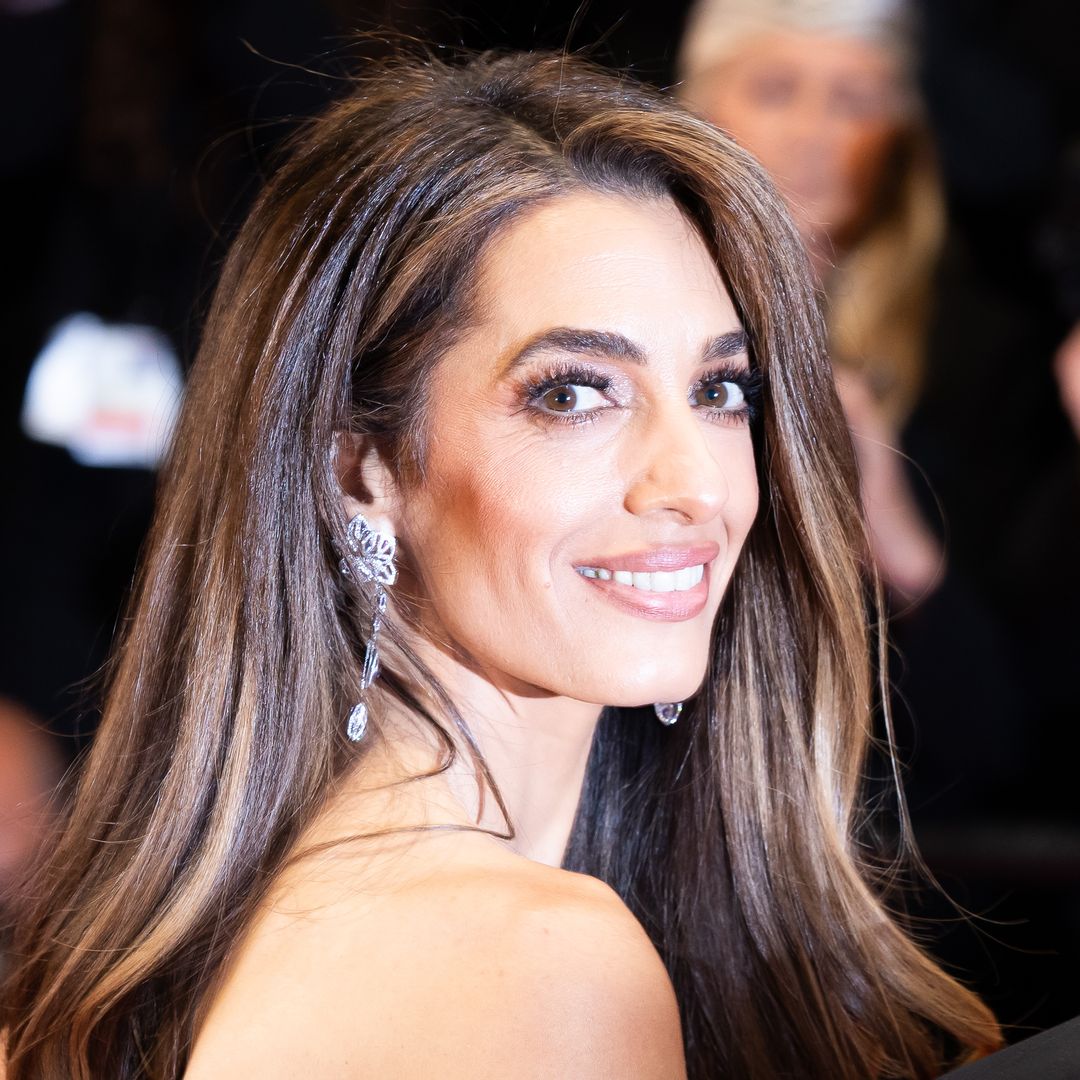 Amal Clooney has a bridal moment in slinky white dress with flowers in hand beside George in Lake Como