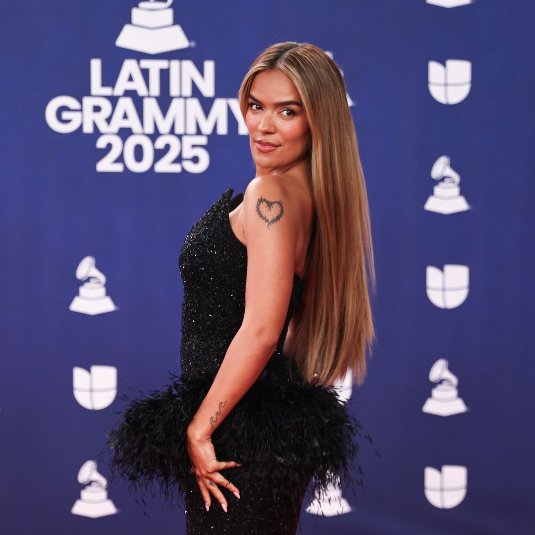 Karol G turns heads in dramatic black feathered gown with emerald accessories at the Latin Grammys