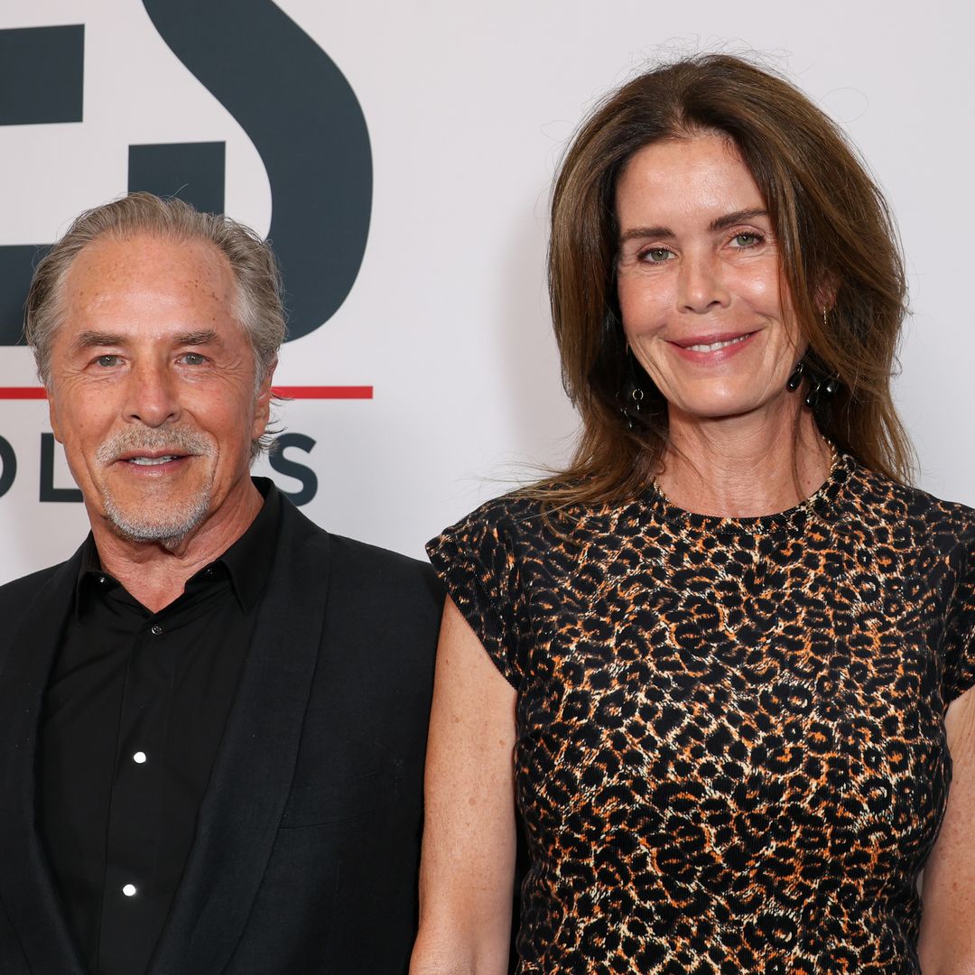 Don Johnson looks like a mid-size king standing next to his wife at a red carpet