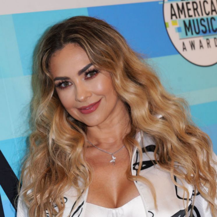 Aracely Arámbula con cabello suelto con ondas y jacket blanca 