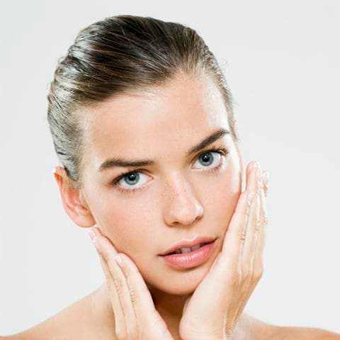 A young woman performing skincare