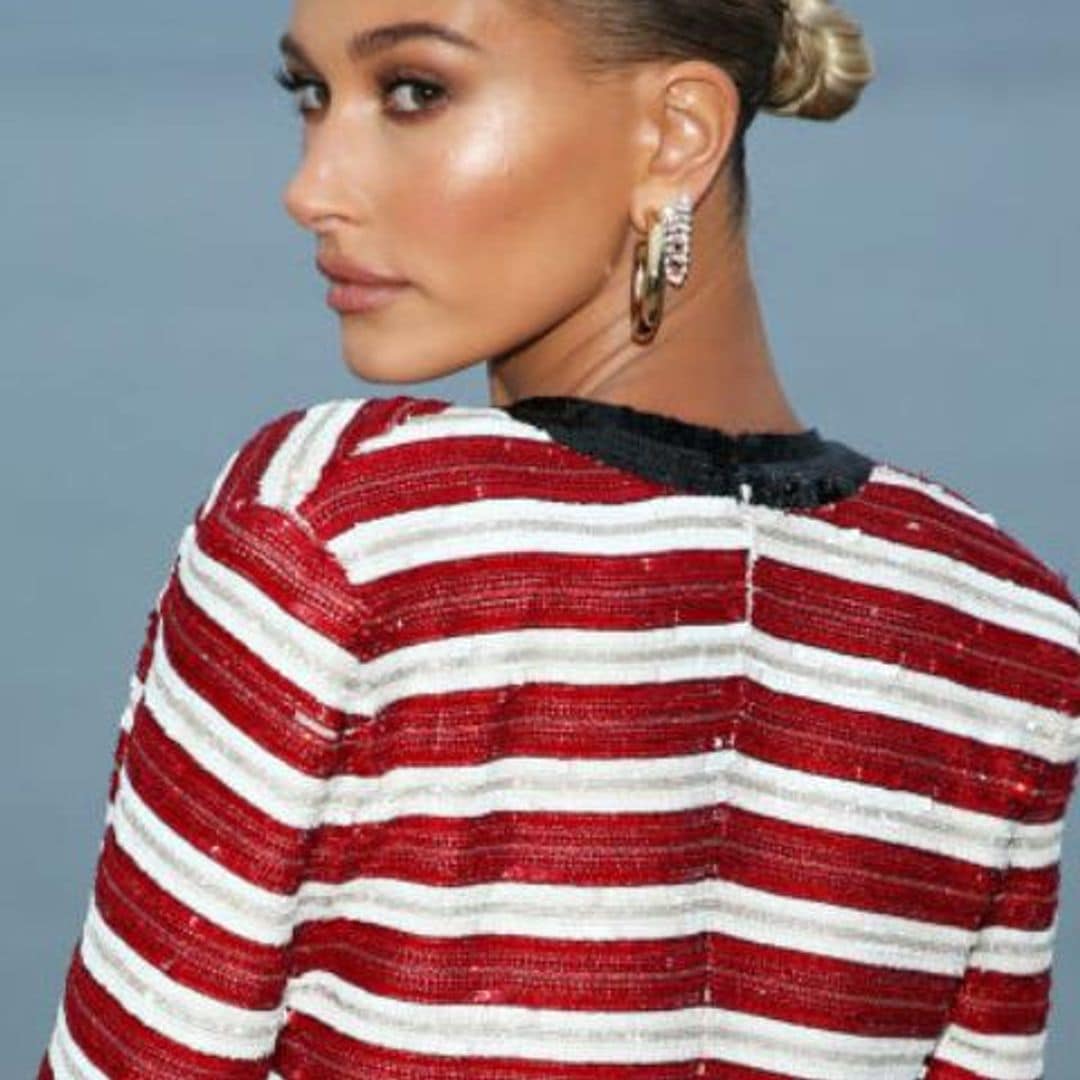 Hailey Baldwin con moño bajo, engominado y vestido de rayas