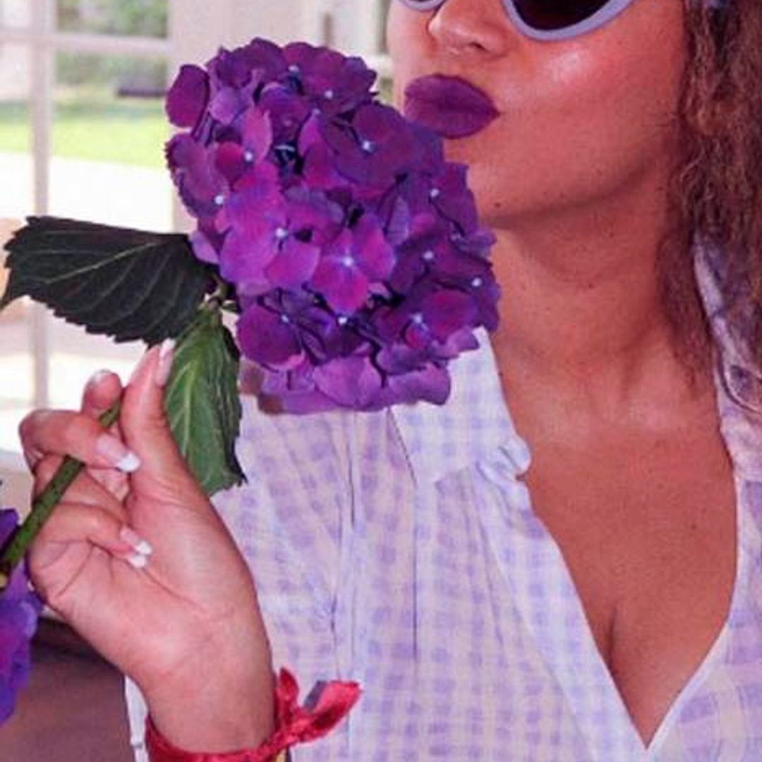 Beyonce con labios morados a juego con unas hortensias
