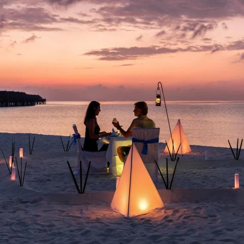 Una pareja disfruta del atardecer en una playa de arena blanca