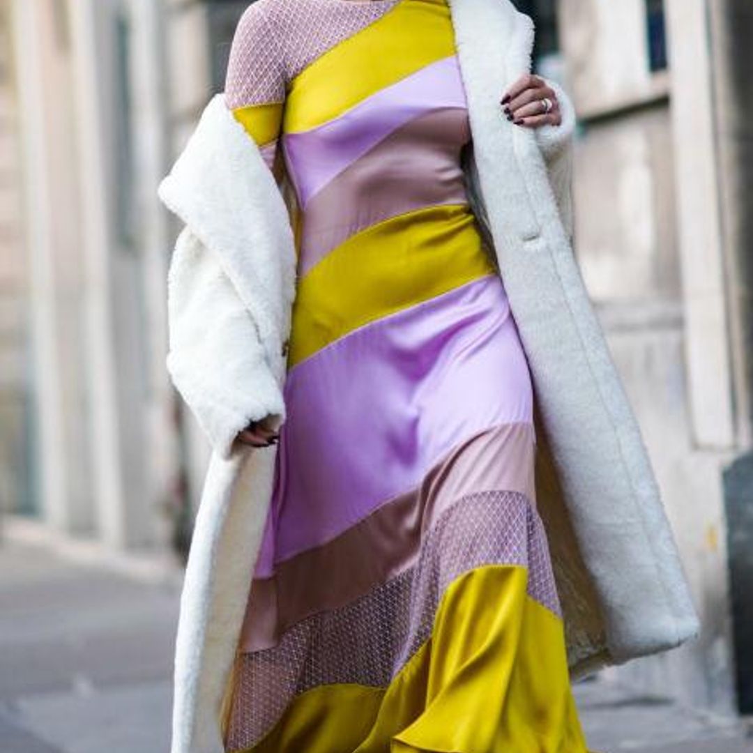 Mujer en el street style con vestido de rayas y de satén, abrigo y botines