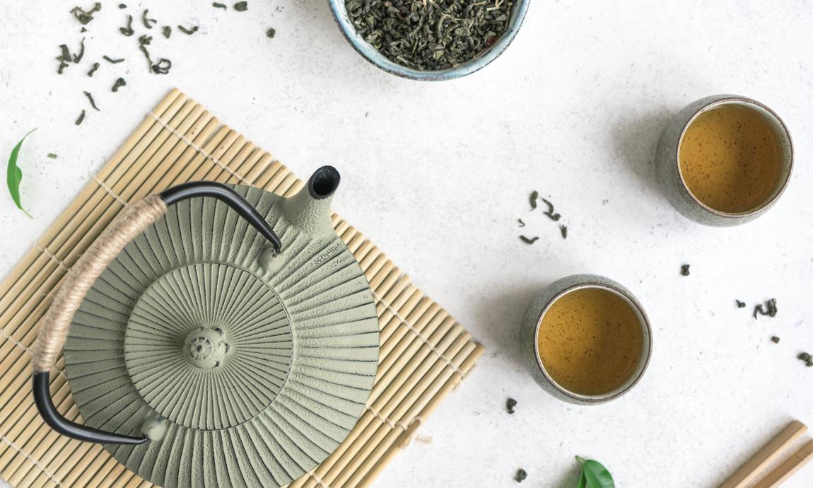 Juego de té asiático: tetera de hierro y tazas de té de cerámica con té verde.