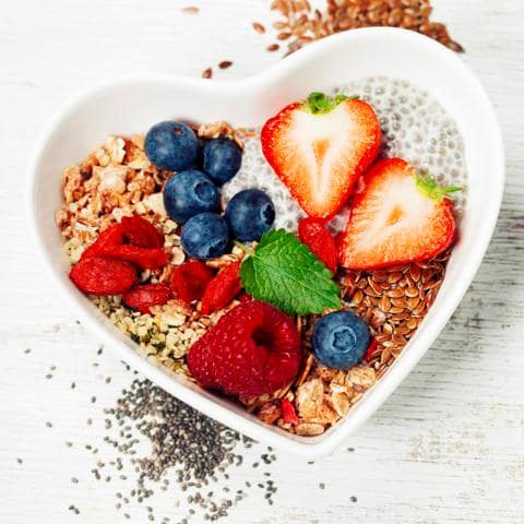 Healthy breakfast of muesli, berries with yogurt and seeds on white background