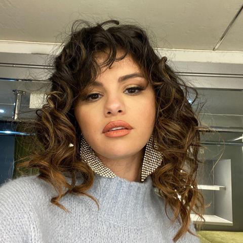 Selena Gomez wearing big silver earring and loose curly hair