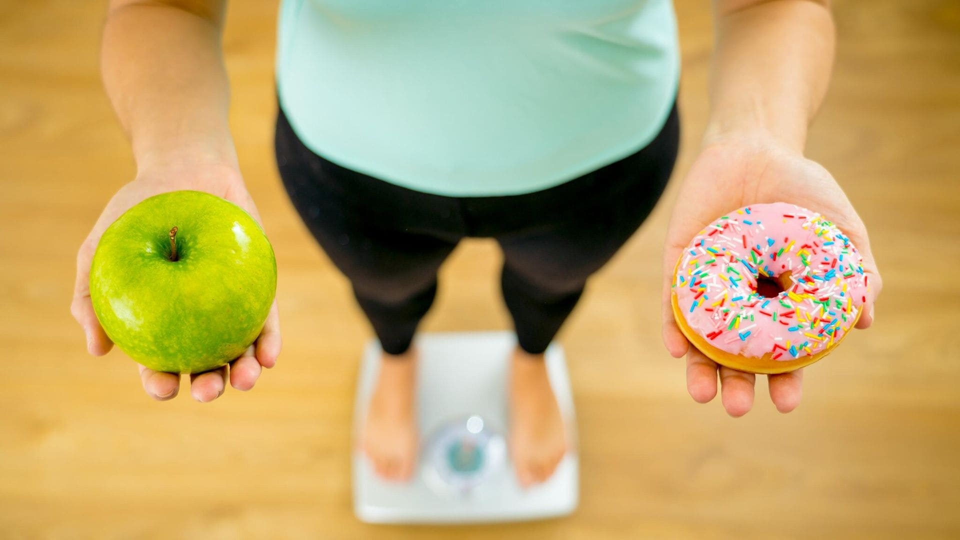 Mujer sobre una báscula sosteniendo en las manos manzana y donut