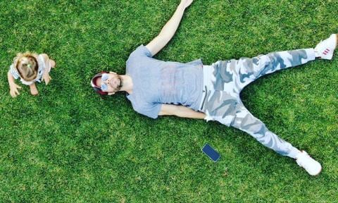 Enrique Iglesias lays on the grass while twins play