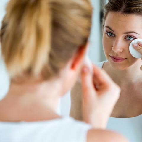 Mujer se limpia su cara frente al espejo