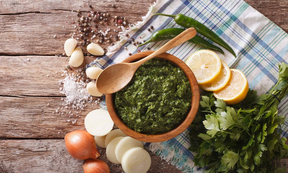 Green spicy sauce chimichurri and ingredients close-up on the table. horizontal view from above