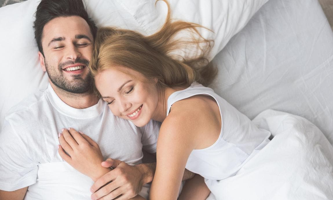 Woman and man waking up happy and cuddling