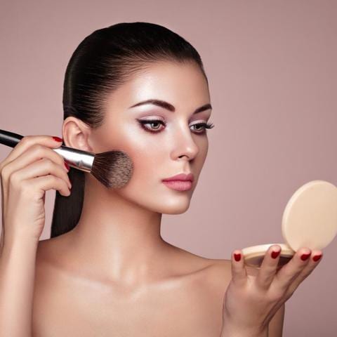 Mujer aplica maquillaje en sus mejillas