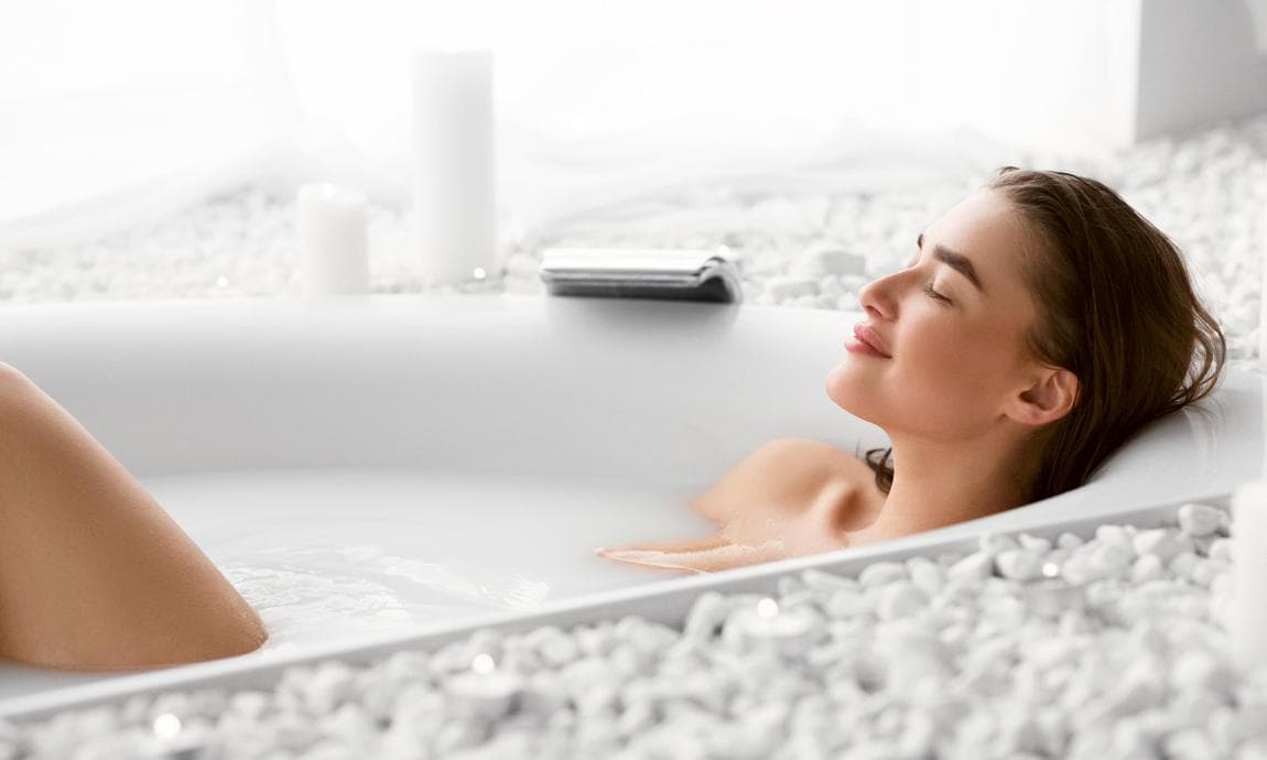 Mujer tomando un baño de agua caliente relajada y feliz