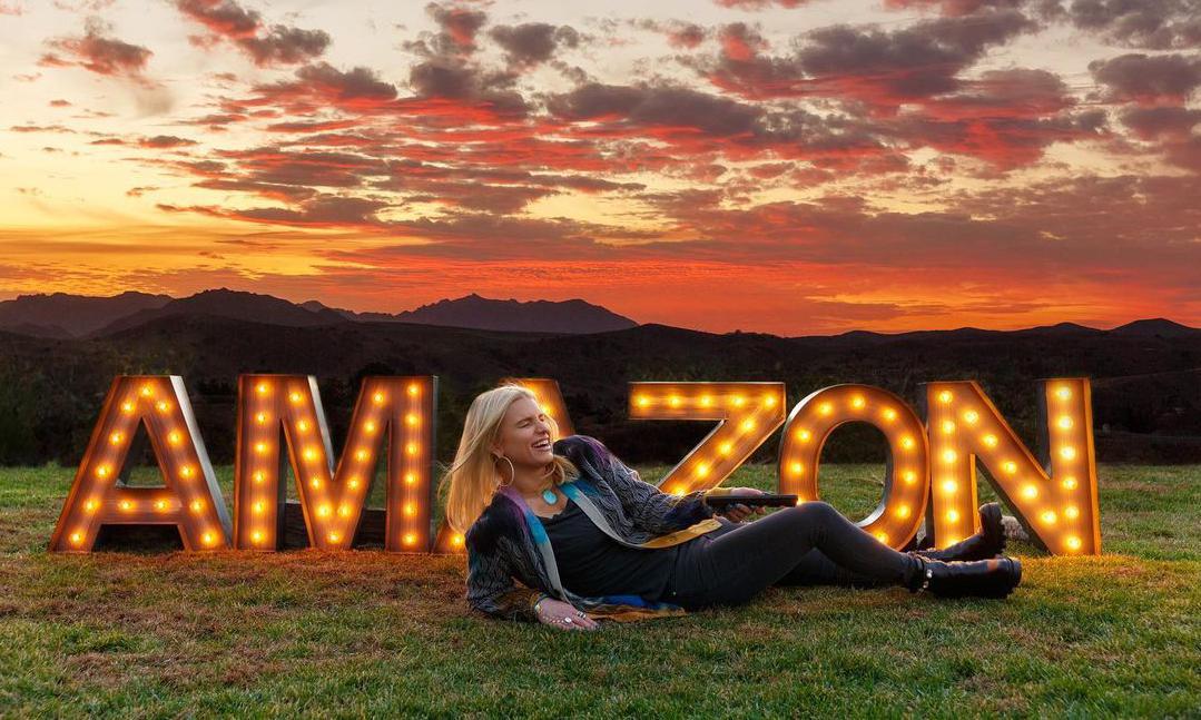 Jessica Simpson posing in front of Amazon sign