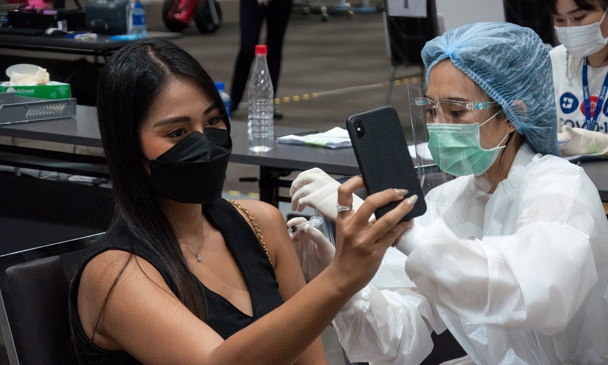 A woman takes a selfie of herself while being administered