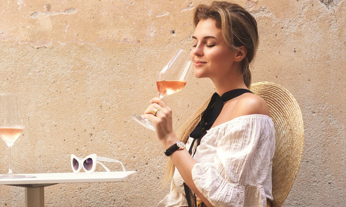 Young woman is drinking rose wine in the street bar
