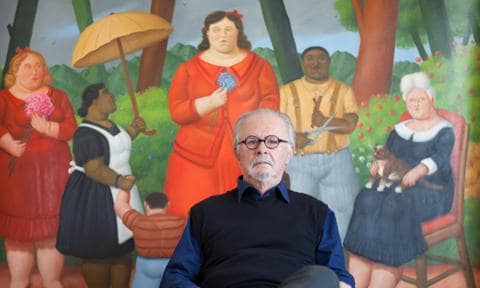 Fernando Botero sitting at his studio in front of a painting