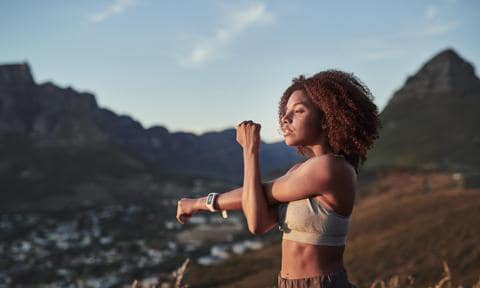Shot of a young woman stretching while out for a workout on a mountain road